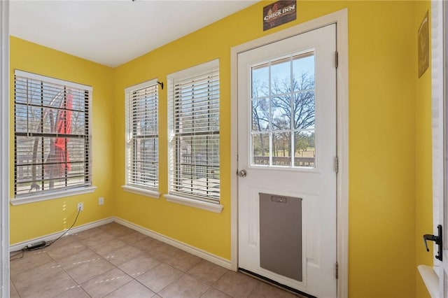 doorway to outside with light tile patterned flooring and baseboards