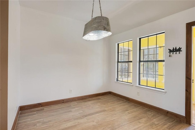 unfurnished room featuring baseboards and light wood finished floors