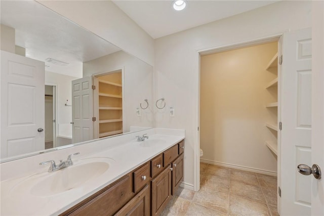 full bathroom with baseboards, a sink, a spacious closet, and toilet