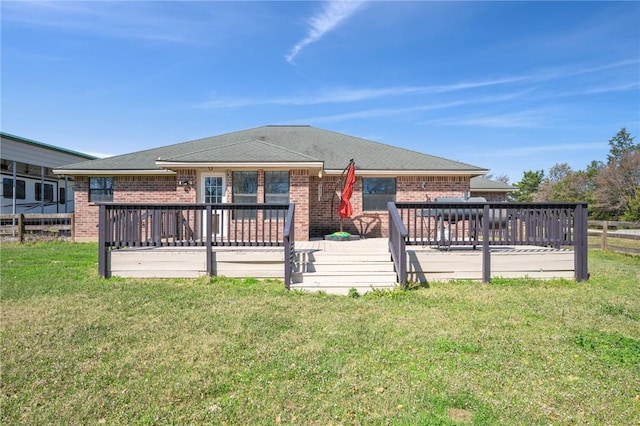 rear view of property with brick siding, a lawn, and a deck