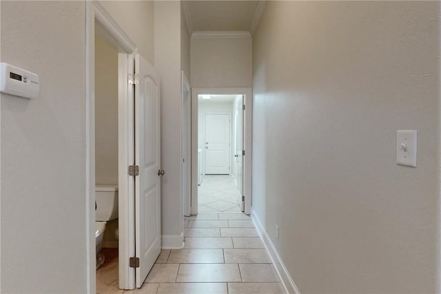 corridor with crown molding, baseboards, and light tile patterned flooring
