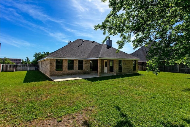 rear view of property with a lawn, a patio, a fenced backyard, and brick siding
