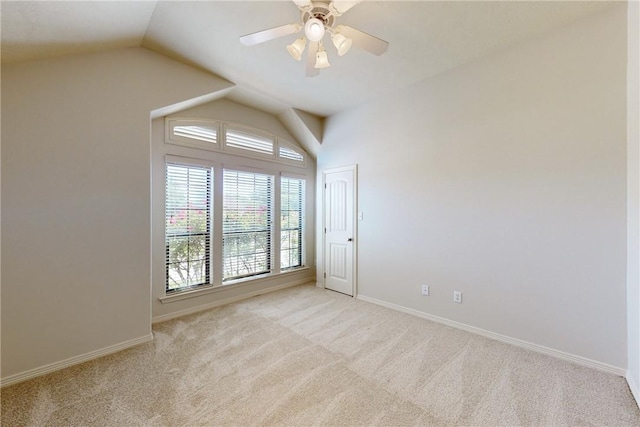 empty room featuring ceiling fan, vaulted ceiling, light carpet, and baseboards