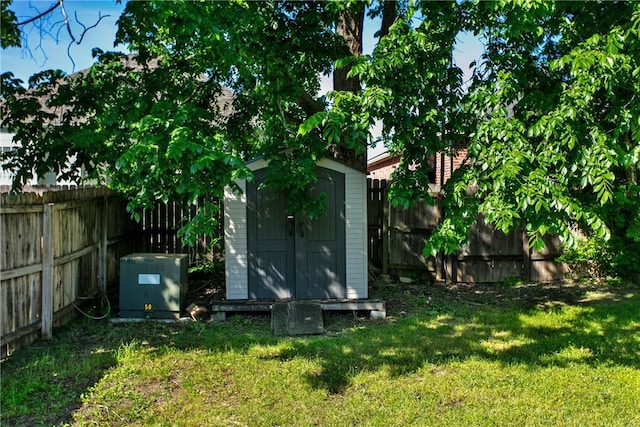 view of yard featuring an outdoor structure, a fenced backyard, and a shed