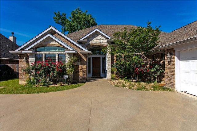 view of front of house with brick siding, an attached garage, driveway, and stone siding