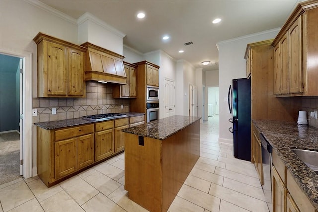kitchen with visible vents, crown molding, a kitchen island, dark stone countertops, and stainless steel appliances