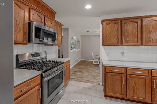 kitchen with backsplash, light tile patterned flooring, and appliances with stainless steel finishes