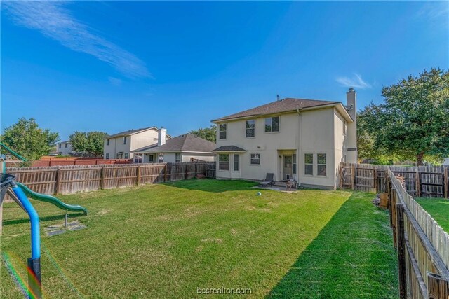 back of house featuring a playground and a yard