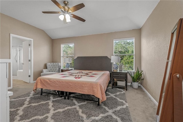 carpeted bedroom with multiple windows, ceiling fan, ensuite bathroom, and vaulted ceiling