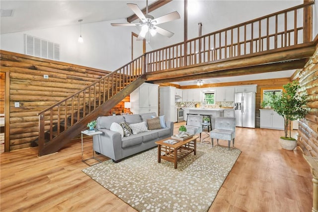 6508 Old Independence Rd, Brenham, TX 77833 - living area featuring rustic walls, high vaulted ceiling, a ceiling fan, stairway, and light wood finished floors