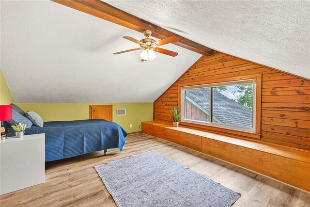6508 Old Independence Rd, Brenham, TX 77833 - bedroom featuring wood walls, wood finished floors, a textured ceiling, and ceiling fan