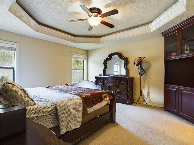 bedroom featuring a tray ceiling, ceiling fan, light carpet, and a textured ceiling