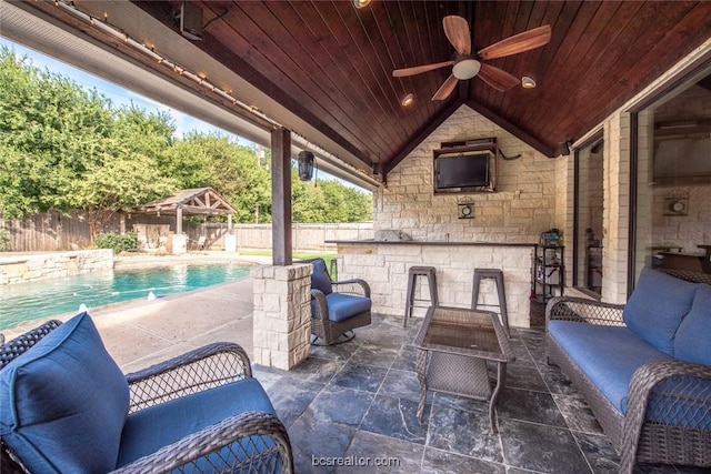 view of patio featuring outdoor lounge area, a bar, a fenced in pool, and ceiling fan