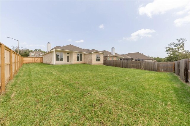 1615 Briscoe Manor Ct, College Station, TX 77845 - back of house featuring a fenced backyard, a chimney, and a lawn