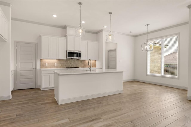 1615 Briscoe Manor Ct, College Station, TX 77845 - kitchen featuring light wood-style flooring, white cabinetry, stainless steel microwave, backsplash, and light countertops