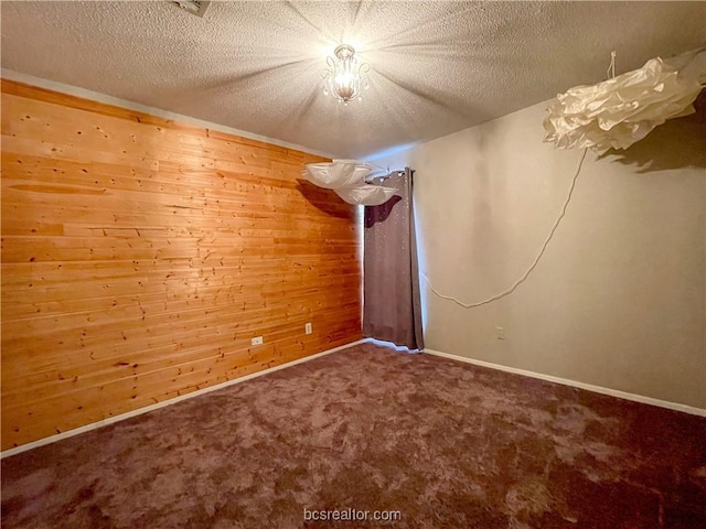 unfurnished room featuring wood walls, carpet floors, and a textured ceiling