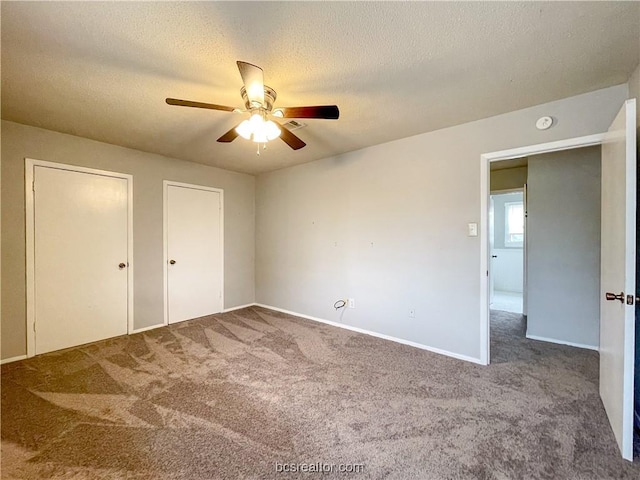 unfurnished bedroom with carpet flooring, a textured ceiling, ceiling fan, and multiple closets