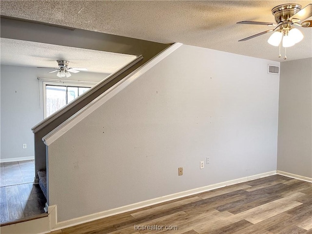 unfurnished room with hardwood / wood-style flooring, ceiling fan, and a textured ceiling