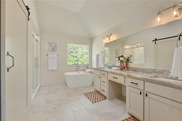 6209 Cromwell Ct, Bryan, TX 77802 - full bath with a stall shower, tile walls, double vanity, lofted ceiling, and a freestanding tub