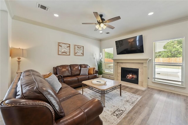 living room with ceiling fan, ornamental molding, and light wood-type flooring