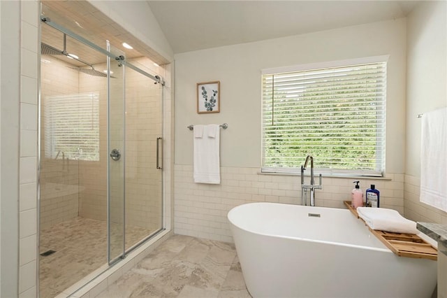 bathroom featuring lofted ceiling, independent shower and bath, and tile walls