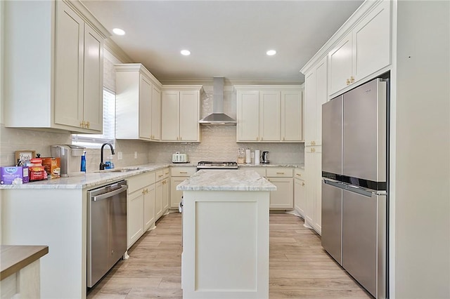 kitchen featuring a center island, wall chimney exhaust hood, light hardwood / wood-style flooring, and appliances with stainless steel finishes