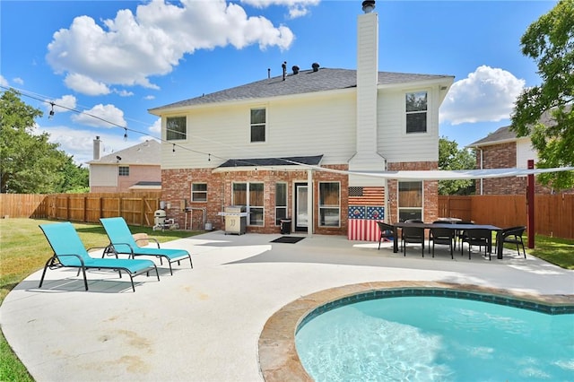 rear view of property with a fenced in pool and a patio area