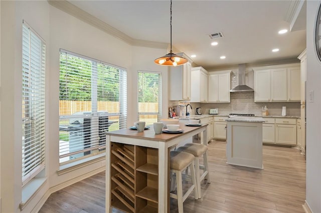 6209 Cromwell Ct, Bryan, TX 77802 - kitchen with wall chimney range hood, crown molding, a kitchen island, tasteful backsplash, and plenty of natural light