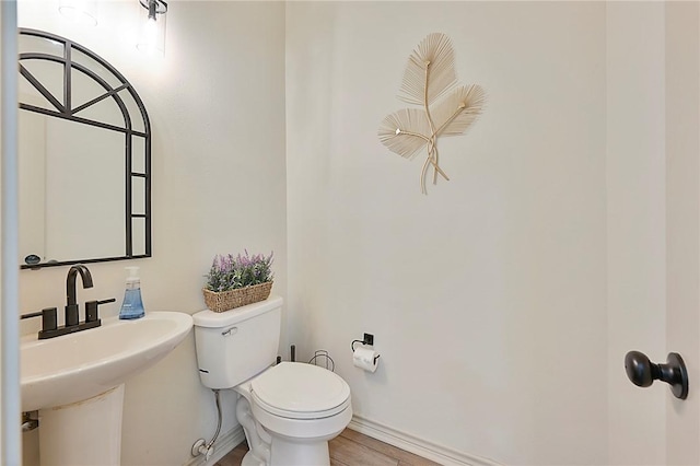 bathroom with hardwood / wood-style flooring, toilet, and sink