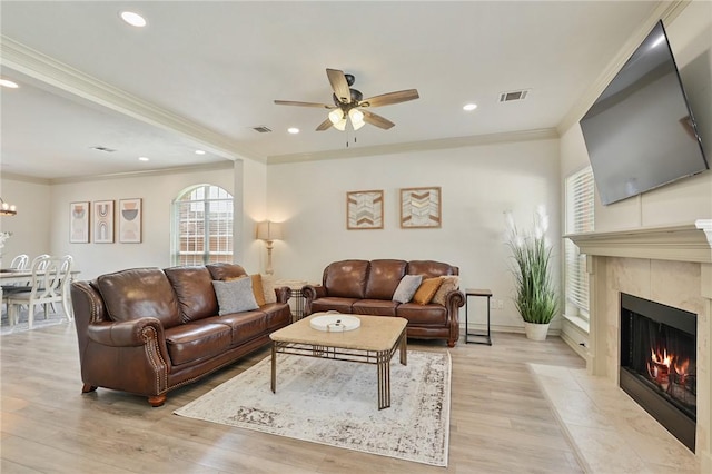 living room with a fireplace, ceiling fan with notable chandelier, light hardwood / wood-style flooring, and ornamental molding