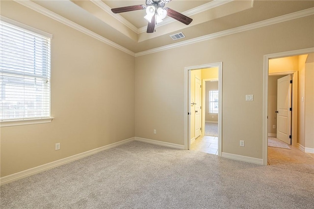 carpeted empty room featuring crown molding, ceiling fan, and a tray ceiling