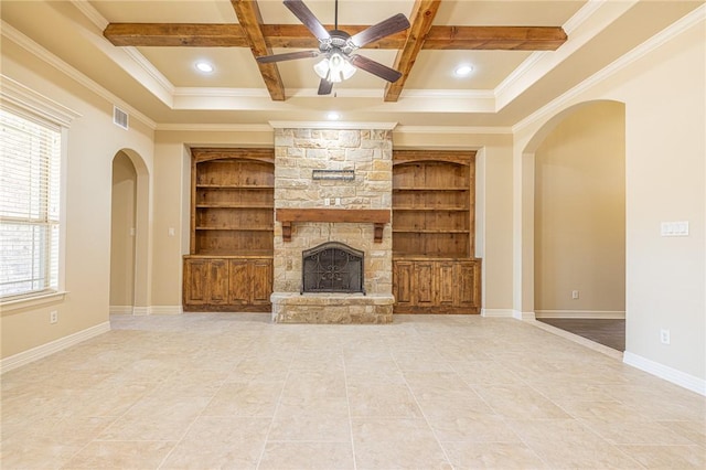 unfurnished living room with a stone fireplace, built in features, beamed ceiling, coffered ceiling, and ceiling fan