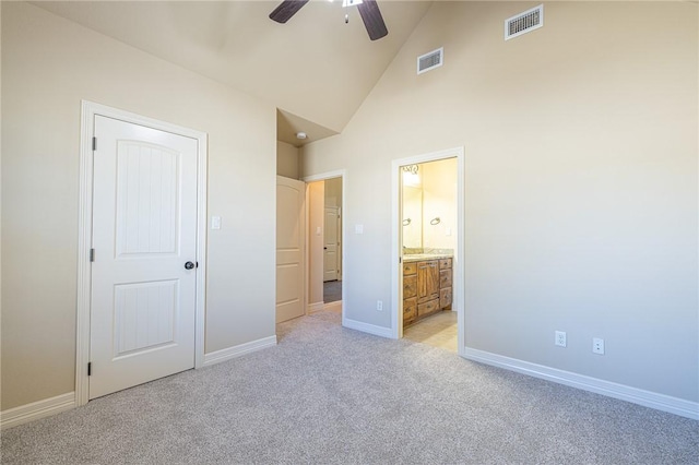 unfurnished bedroom featuring light carpet, ensuite bath, high vaulted ceiling, and ceiling fan