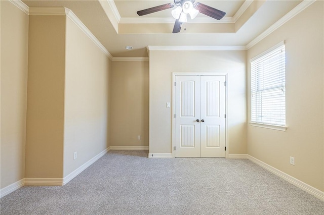 unfurnished bedroom featuring a closet, crown molding, light colored carpet, and a raised ceiling