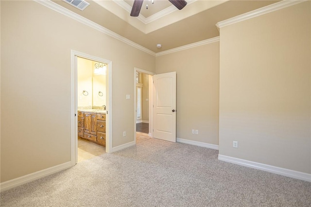 unfurnished bedroom featuring ensuite bath, ceiling fan, ornamental molding, light colored carpet, and a raised ceiling