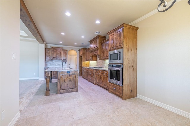 kitchen featuring a breakfast bar, decorative backsplash, light stone counters, stainless steel appliances, and a center island with sink