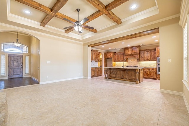 unfurnished living room with coffered ceiling, sink, ornamental molding, beamed ceiling, and ceiling fan