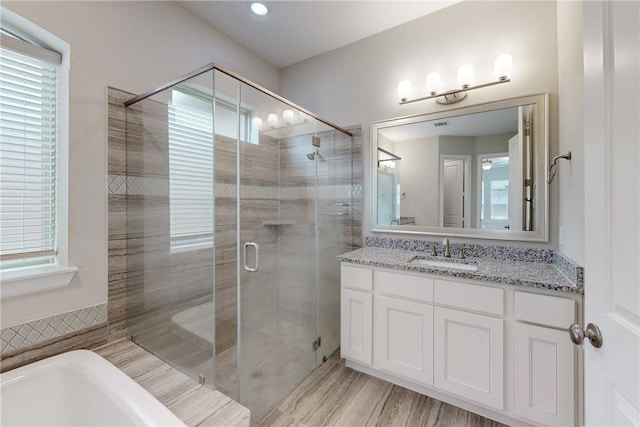 bathroom featuring a shower with door, plenty of natural light, wood-type flooring, and vanity