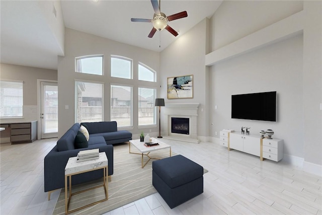 living room with ceiling fan, a wealth of natural light, and a towering ceiling