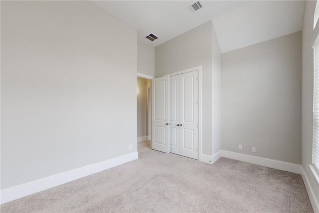 unfurnished bedroom featuring light colored carpet and a closet