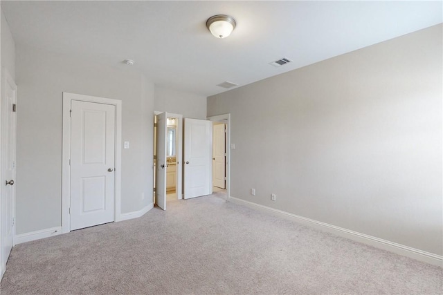 unfurnished bedroom with light colored carpet and a closet