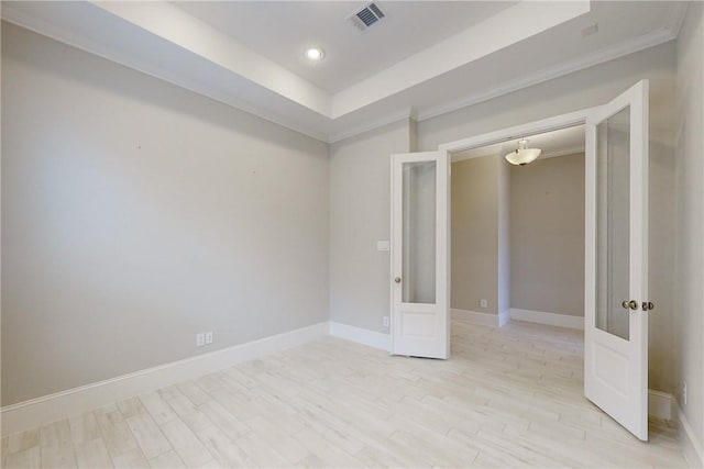 spare room featuring light hardwood / wood-style flooring, a tray ceiling, and ornamental molding