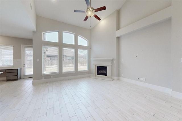 unfurnished living room featuring light wood-type flooring, ceiling fan, and high vaulted ceiling