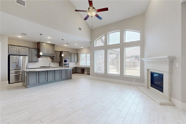 unfurnished living room with ceiling fan, light hardwood / wood-style flooring, and a towering ceiling