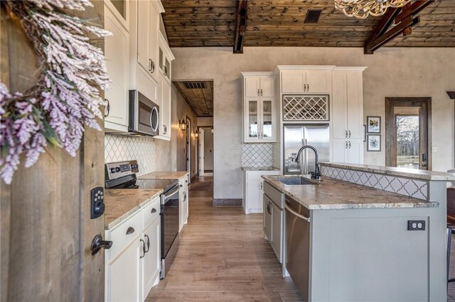 kitchen with wooden ceiling, a center island with sink, stainless steel appliances, and light wood-type flooring