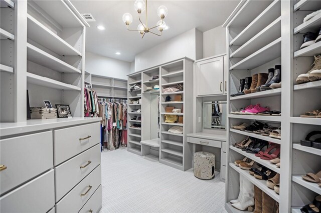 spacious closet with a notable chandelier and light colored carpet