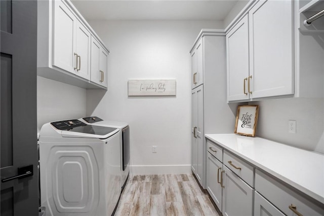 washroom featuring light hardwood / wood-style floors, cabinets, and washing machine and clothes dryer