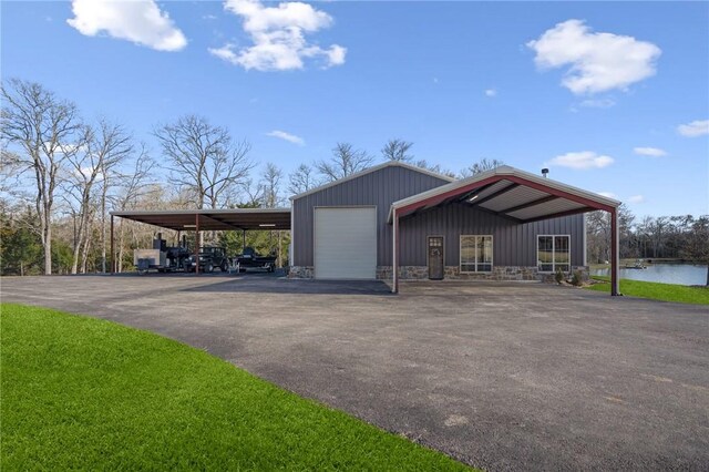 view of property exterior featuring an outbuilding, a water view, a carport, and a garage