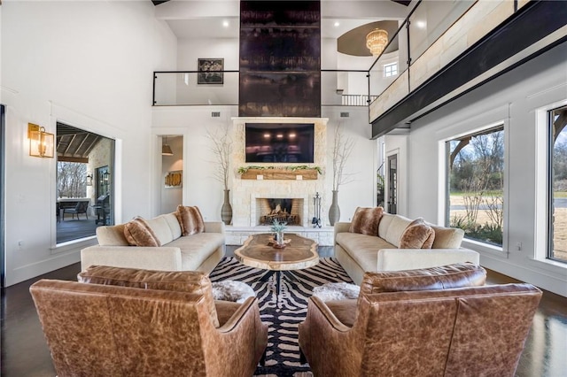 living room featuring hardwood / wood-style flooring, a stone fireplace, and a high ceiling