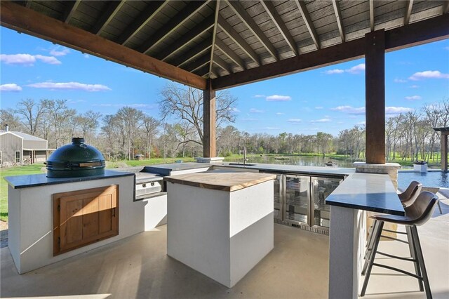 view of patio / terrace with area for grilling, a water view, and a wet bar